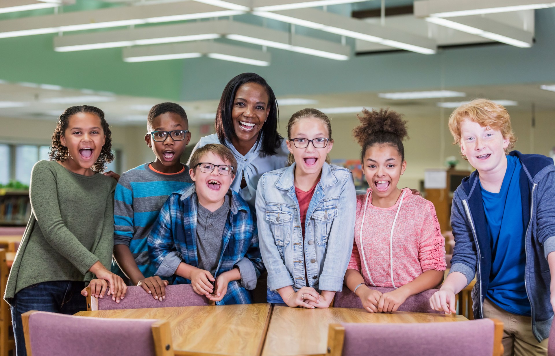 Boy with down syndrome, teacher, classmates in library